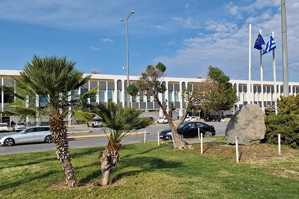 Heraklion Airport main building behind palm trees in Crete near car rental pickup area